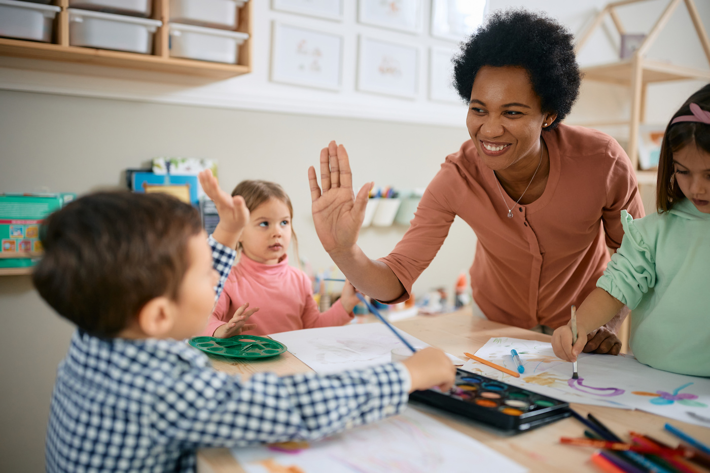 teacher giving a high five to students in a classroom.