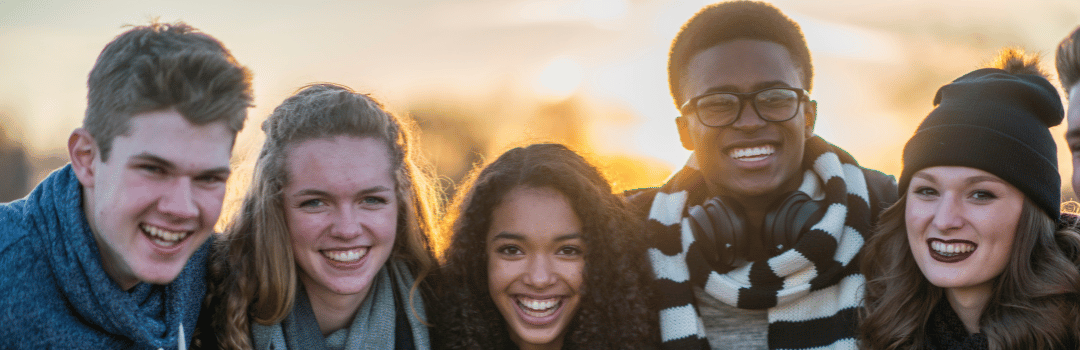 row of smiling teens standing outdoors