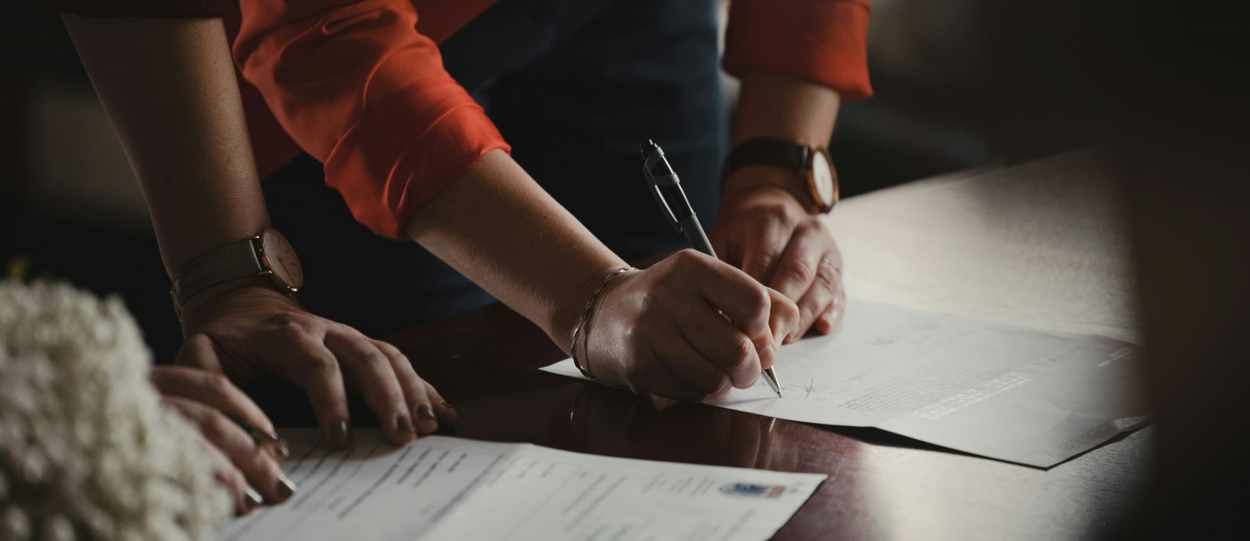 closeup of people signing paperwork