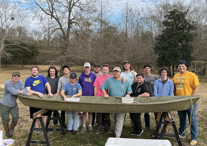 beta theta pi members in front of a boat